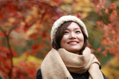 Sonbahar parkında poz veren Asyalı genç kadının portresi. 