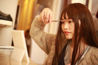 Güzel Asyalı kadın saçını kesiyor. 