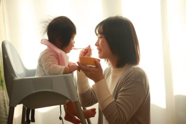 Genç anne, sevimli bebeği evde besliyor.