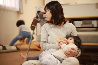 Küçük kızını evde besleyen Asyalı kadın.