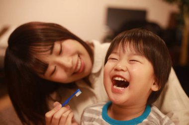 Genç anne, küçük oğlu için dişlerini fırçalıyor.