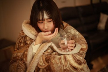 Soğuk algınlığı olan hasta bir kadın ilaç alıyor.