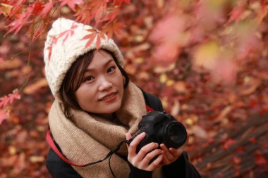 Sonbahar parkında resim çeken Asyalı genç bir kadının portresi. 