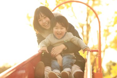 Küçük sevimli Asyalı çocuk ve annesi parkta.