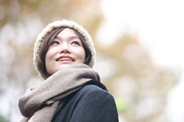 Sonbahar parkında poz veren Asyalı genç kadının portresi. 