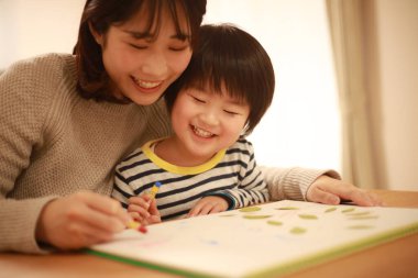 Gülümseyen Asyalı genç kadın ve küçük oğlu el kreması yapıyorlar. 