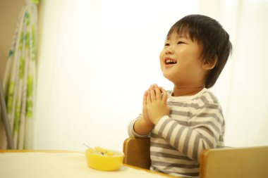 Tatlı Asyalı çocuk evde yemek yiyor.