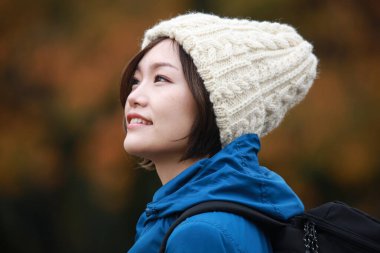 Sonbahar parkında poz veren Asyalı genç kadının portresi. 