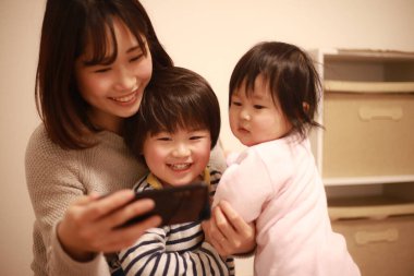 Mutlu Asyalı aile televizyon izlemek için cep telefonu kullanıyor.