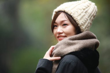 Sonbahar parkında poz veren Asyalı genç kadının portresi. 