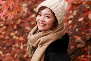 Sonbahar parkında poz veren Asyalı genç kadının portresi. 