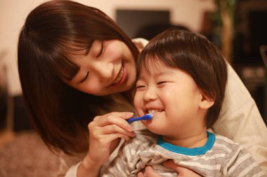 Genç anne, küçük oğlu için dişlerini fırçalıyor.
