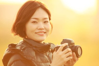 Kameralı güzel Asyalı kadın portresi ve şehrin arka planında fotoğraflar..