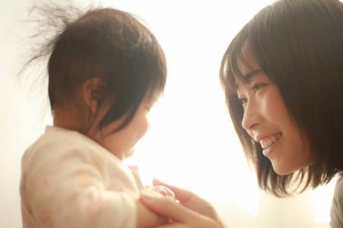 Güzel genç anne pencere ışığında kızıyla oynuyor.  