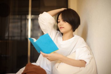 Kanepede kitap okuyan güzel bir kadın.