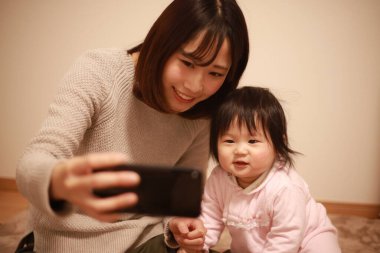 Anne ve kızı cep telefonuyla selfie çekiyorlar.