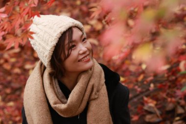 Sonbahar parkında poz veren Asyalı genç kadının portresi. 