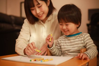 Beyaz kağıda boya kalemleri çizen genç anne ve oğul.
