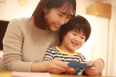 Gülümseyen Asyalı genç kadın ve küçük oğlu el kreması yapıyorlar. 