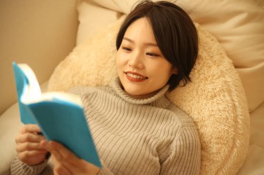 Kanepede kitap okuyan güzel bir kadın.