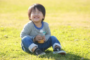 Parkta meyve suyu içen mutlu çocuk portresi