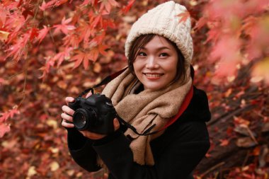 Sonbahar parkında resim çeken Asyalı genç bir kadının portresi. 