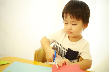 Asyalı bebek makasla oynuyor.