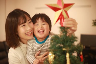 Asyalı anne ve oğlu Noel ağacı süslüyorlar.