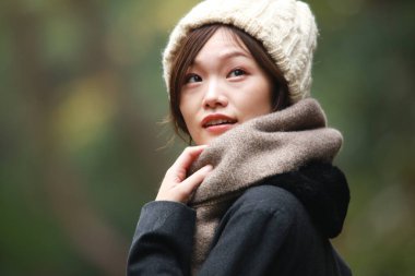 Sonbahar parkında poz veren Asyalı genç kadının portresi. 