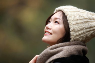 Sonbahar parkında poz veren Asyalı genç kadının portresi. 