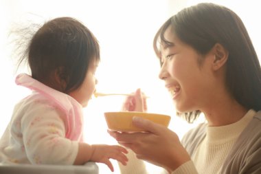 Genç anne, sevimli bebeği evde besliyor.