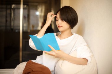 Kanepede kitap okuyan güzel bir kadın.