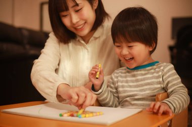 Beyaz kağıda boya kalemleri çizen genç anne ve oğul.