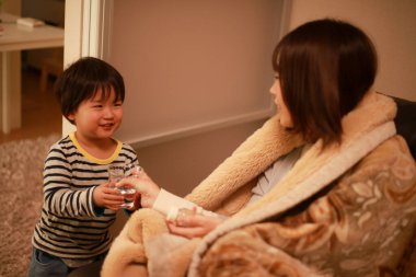 Küçük çocuk hasta annesine yardım ediyor.