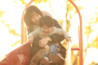 Küçük sevimli Asyalı çocuk ve annesi parkta.