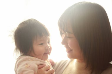 Güzel genç anne pencere ışığında kızıyla oynuyor.  