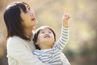 Asyalı anne oğluna sarılıyor.