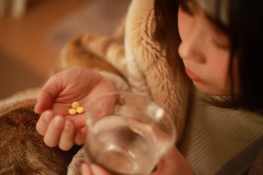 Soğuk algınlığı olan hasta bir kadın ilaç alıyor.