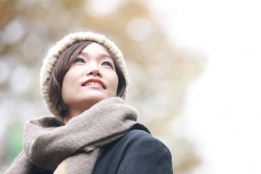 Sonbahar parkında poz veren Asyalı genç kadının portresi. 