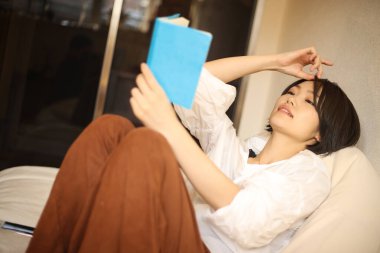 Kanepede kitap okuyan güzel bir kadın.