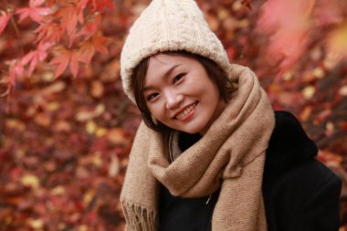 Sonbahar parkında poz veren Asyalı genç kadının portresi. 