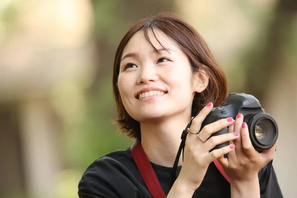 公園のカメラを持った若いアジア人女性の肖像画です — ストック写真