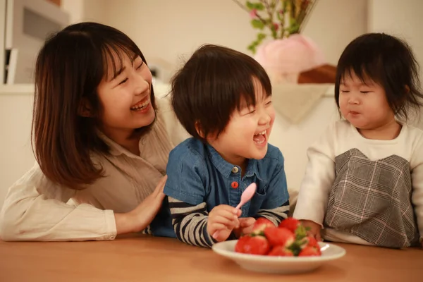 アジアの女性と子供たちがイチゴを食べ — ストック写真