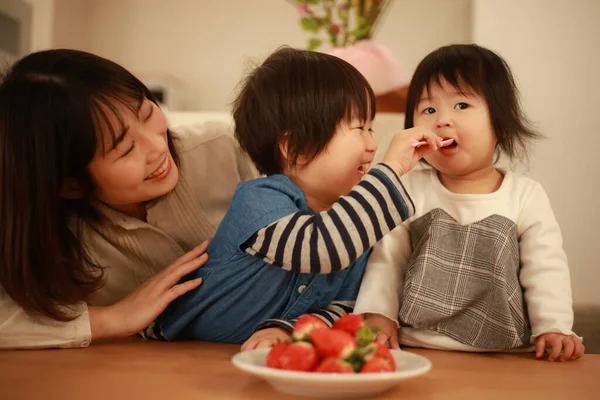 アジアの女性と子供たちがイチゴを食べ — ストック写真
