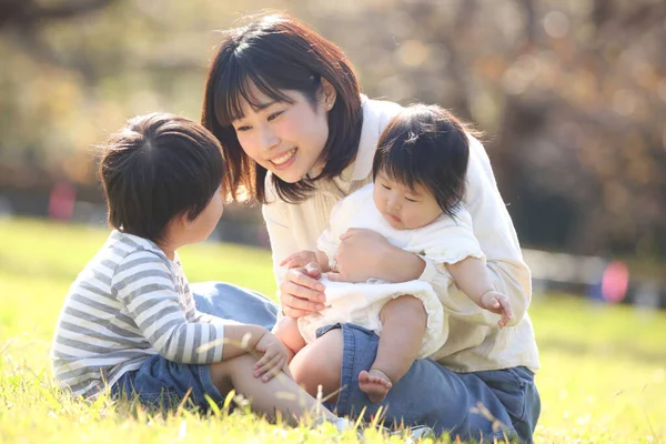 公園で母親と一緒に暮らすアジア系の子供たちは — ストック写真