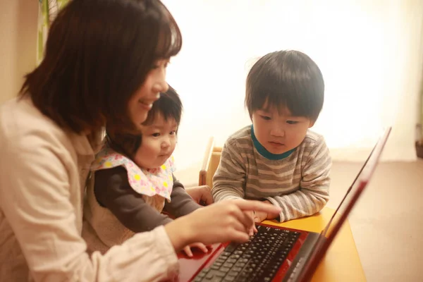 快乐的日本母亲与孩子一起使用笔记本电脑的肖像 — 图库照片