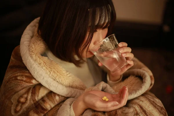 Soğuk algınlığı olan hasta bir kadın ilaç alıyor.