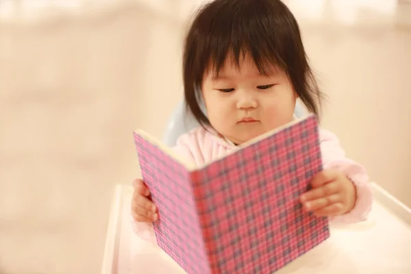 アジア系の少女が部屋で本を読んでいて — ストック写真