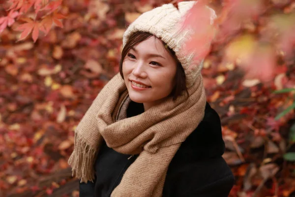 Sonbahar parkında poz veren Asyalı genç kadının portresi. 