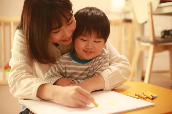 白い紙の上にクレヨンで描く若い母親と息子 — ストック写真